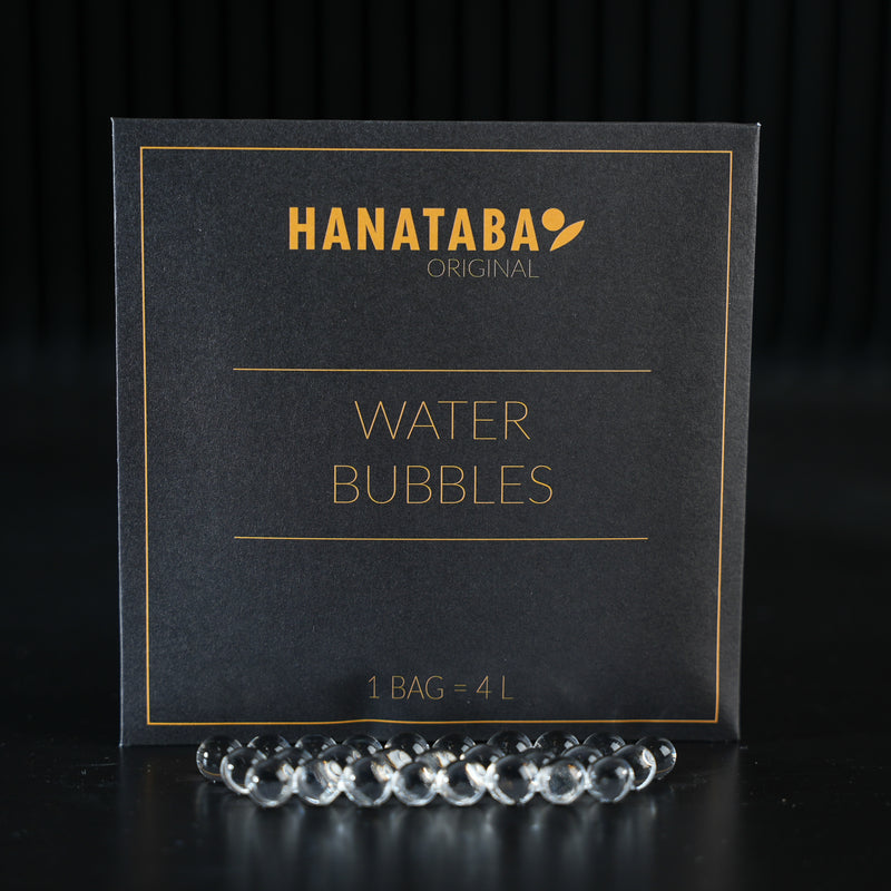 Wyrafinowane opakowanie z etykietą "HANATABA Original Water Bubbles" z napisem "1 BAG = 4L", któremu towarzyszą przezroczyste bąbelki wodne z przodu, przeznaczone do wzbogacania kompozycji kwiatowych.