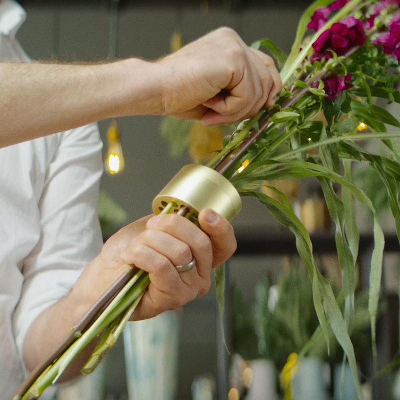 Zbliżenie rąk skrupulatnie mocujących łodygi za pomocą Champagne Gold Hanataba twister.